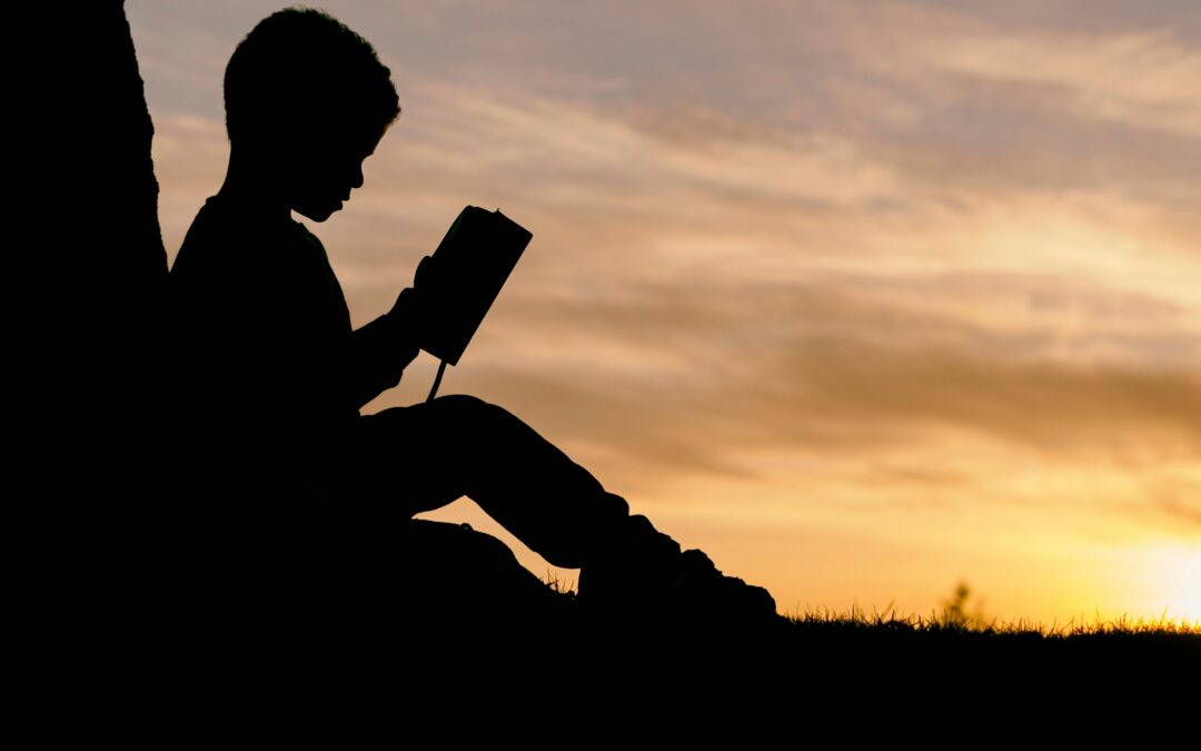 kid reading under a tree